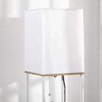 White fabric lampshade on a white frame with wood shelf trim
