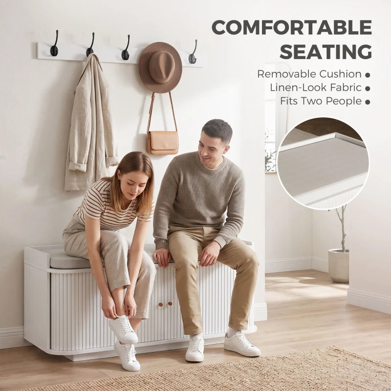White hallway storage bench with padded seat and wall coat hooks for shoes