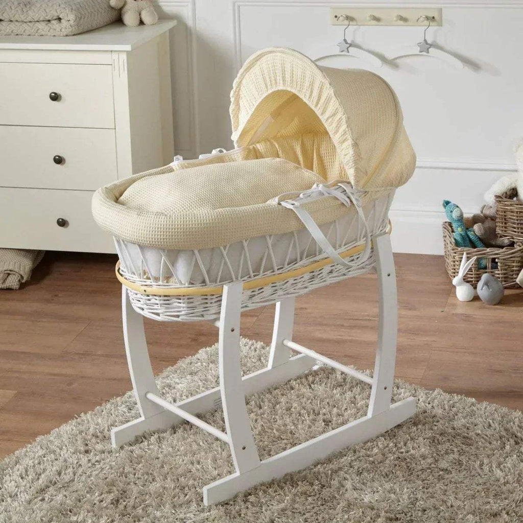 Wicker baby moses basket on white stand with cream bedding and hooded liner