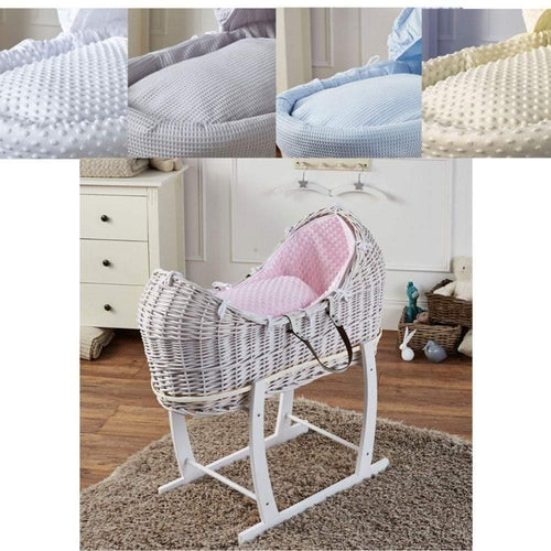 White wicker baby moses basket on a rocking stand with pink waffle bedding