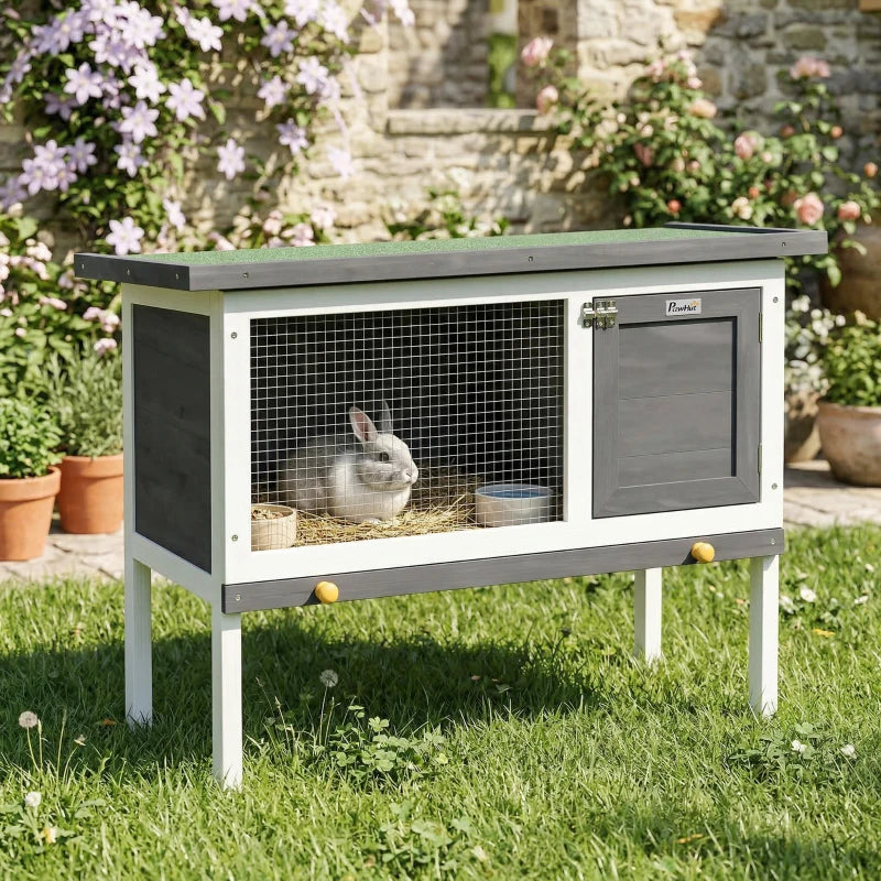 Grey wooden rabbit hutch with wire front and dark door, bunny inside