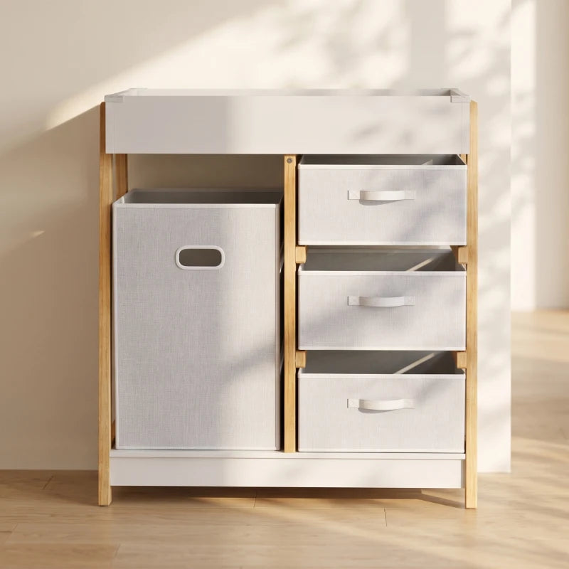 White baby changing table with fabric basket and three front drawers, open top storage.