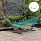 Black metal hammock stand in a garden yard holding a teal striped hammock