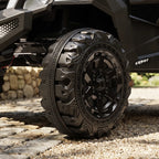 Black ride-on UTV tire and wheel with chunky tread, close-up