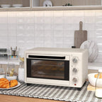 Cream mini countertop oven on counter with glass door and control dials