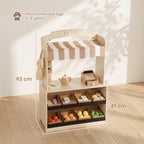 Wooden kids play shop with striped canopy, cash register, and stacked play food pieces
