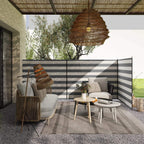 Grey and white striped outdoor privacy windbreak with steel poles, set up on patio