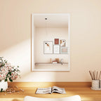 White framed wall mirror reflecting an indoor display shelf