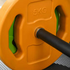 Orange 5KG weight plate with green inserts on a black barbell bar