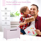 Pink wooden kids toy box with lift-up lid, front handle slot, and safety hinge.