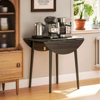 Grey round drop-leaf dining table with wood legs, used as a kitchen coffee station