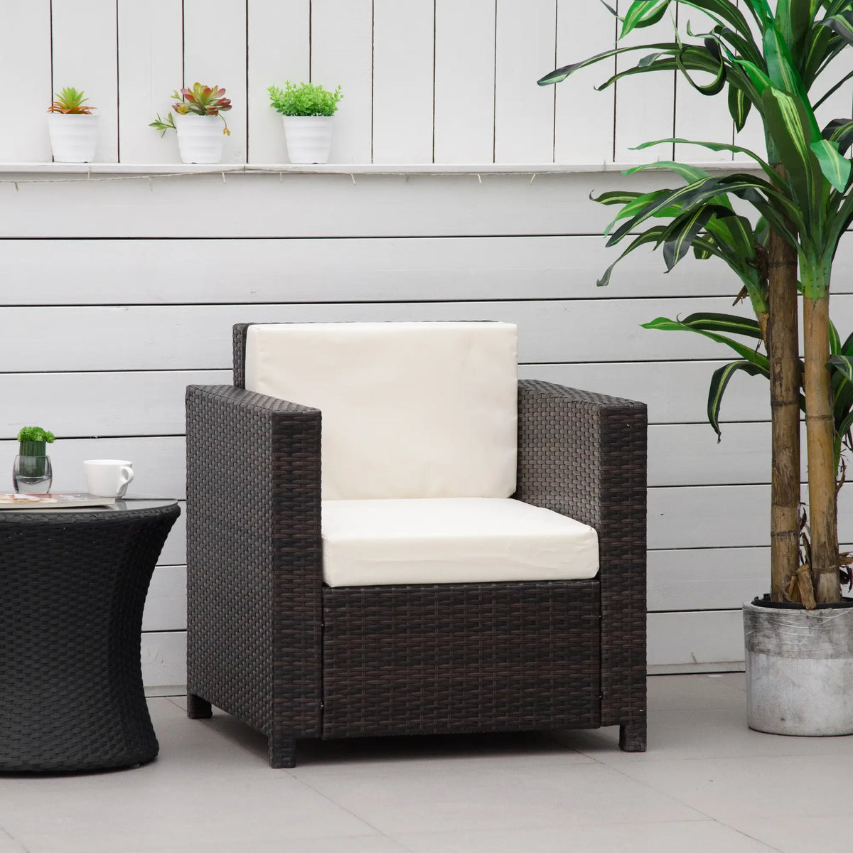Brown wicker garden armchair with white cushions, shown in an outdoor setting