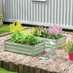 Light green steel raised planter box with blooming flowers in an outdoor garden bed