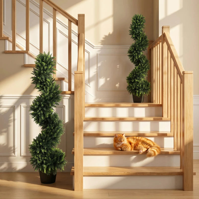 Two deep green artificial cypress trees in black pots placed by stairway