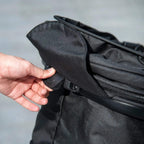Black stroller side latch and canopy area, with hand adjusting the cover