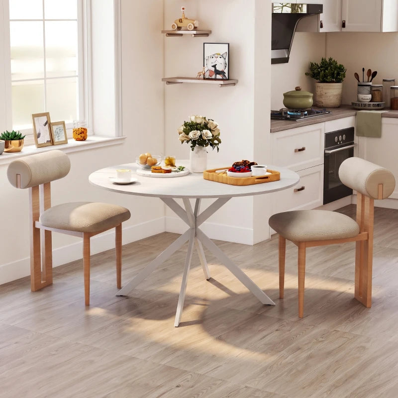 White round dining table with steel legs and beige upholstered bench-style chairs