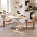 White round dining table with steel legs and beige upholstered bench-style chairs