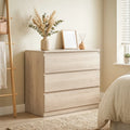 Oak 3-drawer chest with front view and top surface styled with vase and frame.