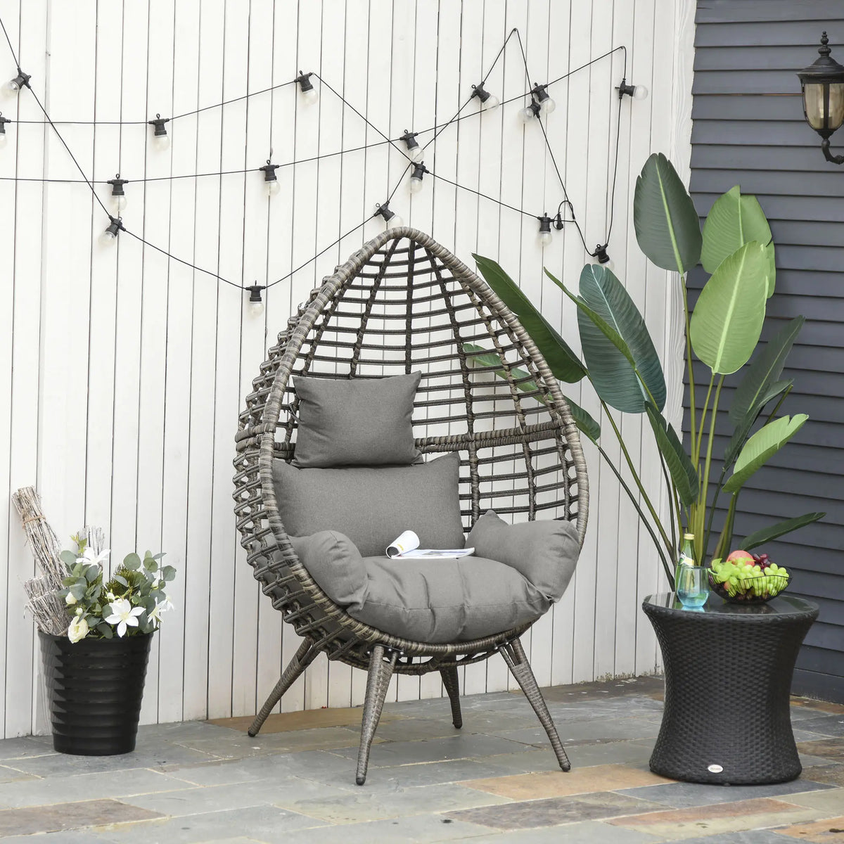 Gray-cushioned teardrop wicker chair shown on a patio