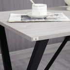 White wood-effect tabletop corner with metal logo plate and black support leg