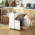 White rolling dining table with light wood tabletop, open shelf, and storage cabinet