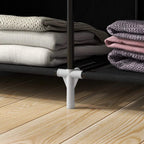 White adjustable feet and metal legs under a black fabric wardrobe for stability.