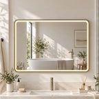 Gold-tone rectangular LED bathroom mirror with warm backlight above the vanity sink.
