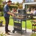 Black 2-burner gas barbecue grill in use with lid open and food on the grate
