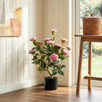 Pink artificial camellia plant with green leaves and pink blossoms in a black pot