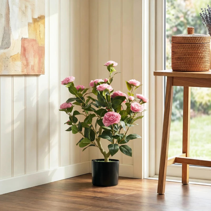 Pink artificial camellia plant with green leaves and pink blossoms in a black pot